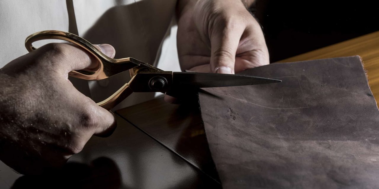 tailor-cutting-leather-with-scissors-min